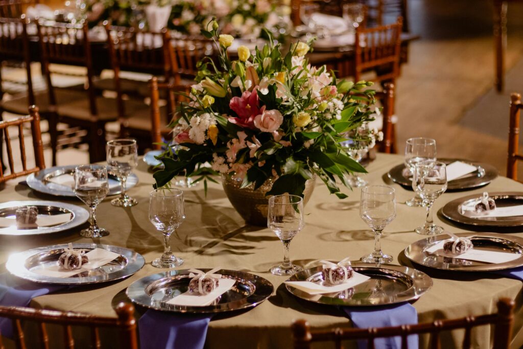 A beautifully set dining table with a colorful floral arrangement and elegant glassware in a restaurant setting.