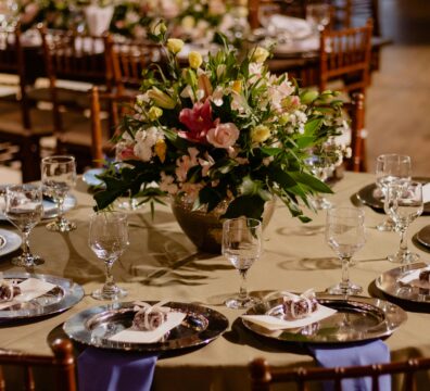A beautifully set dining table with a colorful floral arrangement and elegant glassware in a restaurant setting.